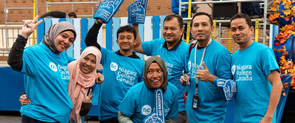 Group of visitors from Indonesia wearing NC t-shirts and waving Go Knights foam fingers